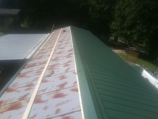 Old rusted panels beside newly installed green metal roofing — Wind Damage Roof Repair by Roofing Brothers in Circle Pines