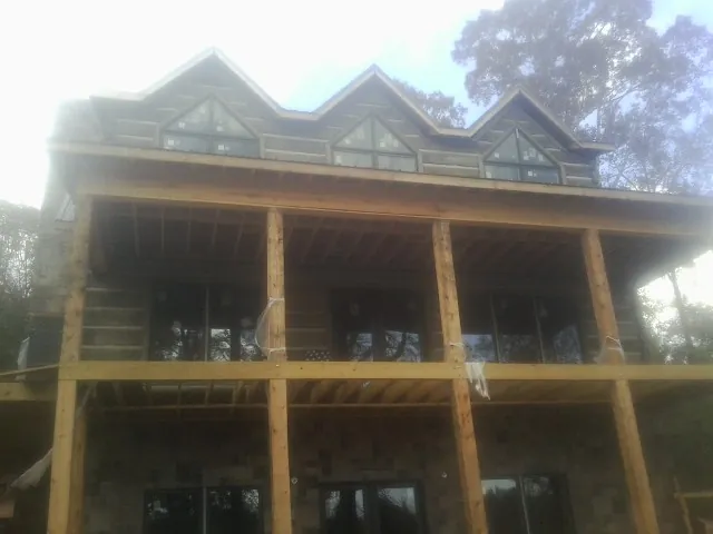 Dormers and porch framing on a large log home under construction — Roof Coating work by our crew in Circle Pines