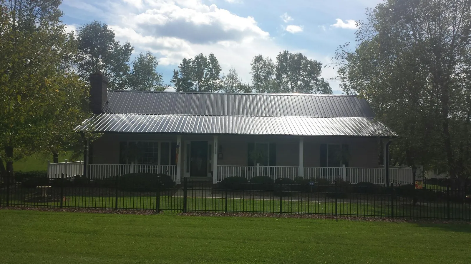 Gray metal roof on a brick ranch with a full width front porch — Gutter Guard Installation work by our crew in Circle Pines