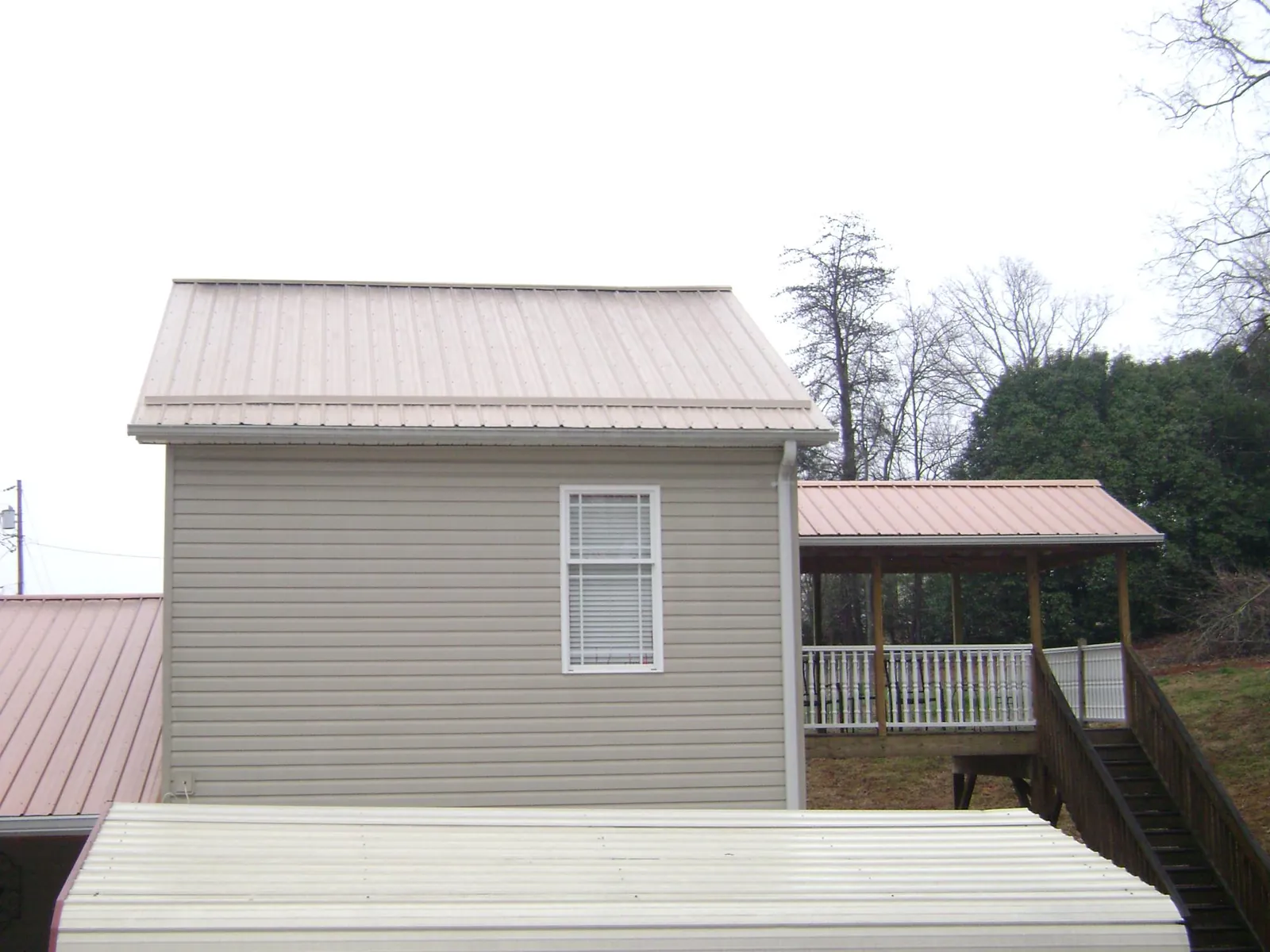 Tan metal roofs on a two story addition and attached porch, from a Roof Replacement job in Circle Pines